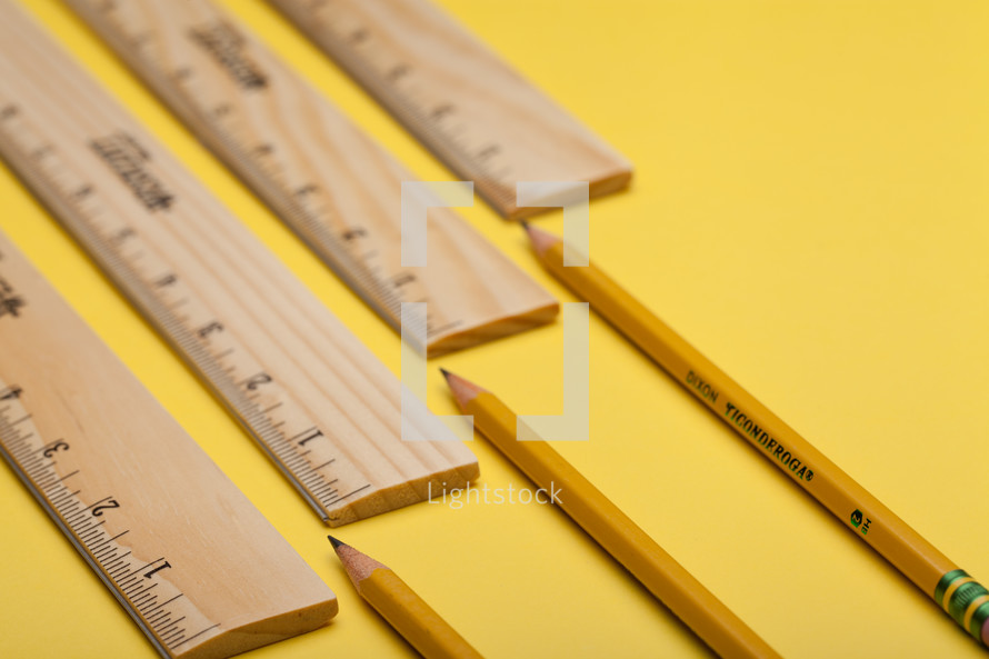 rulers and sharpened pencils on a yellow background 