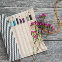 colored pencils in a bag and wildflowers 