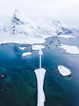aerial view over a bridge leading to a snow covered island 