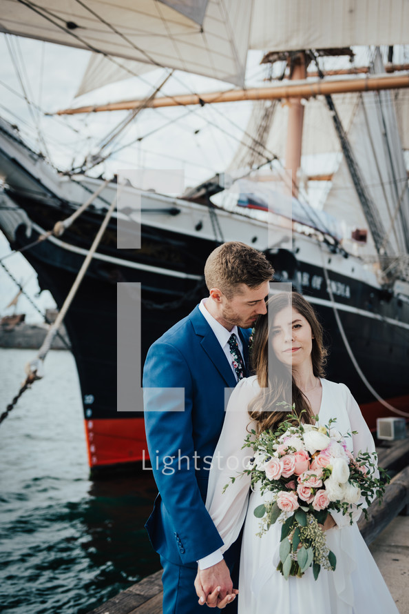 bride and groom in front of a ship 