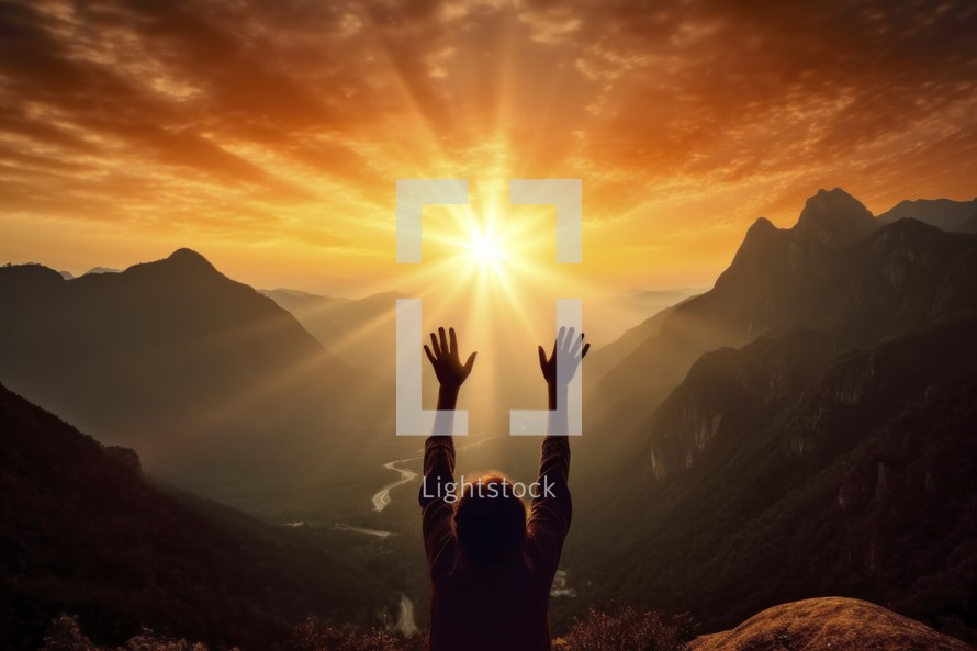 Silhouette of a woman with raised hands in worship against the background of the mountains