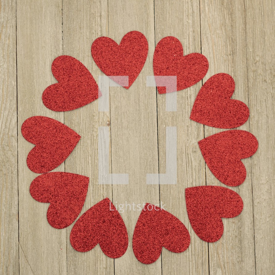 a circle of red hearts on a wood background for a Valentine's day frame
