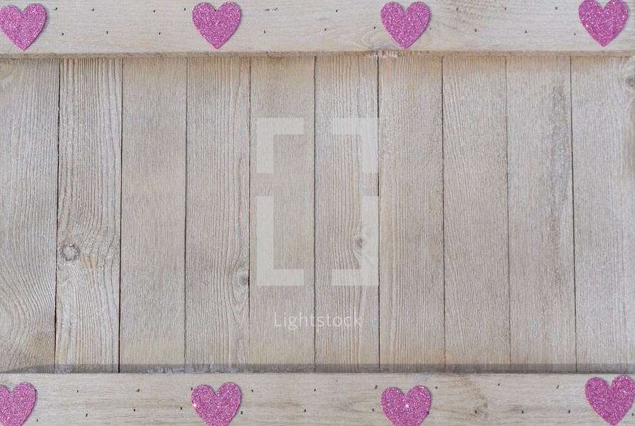 a border of pink hearts on wood background 