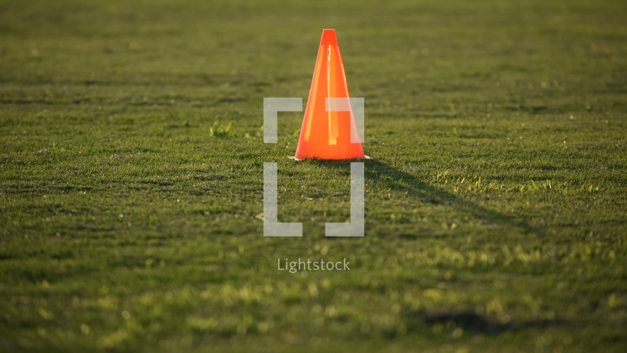 glowing orange cone on a soccer field at sunset 