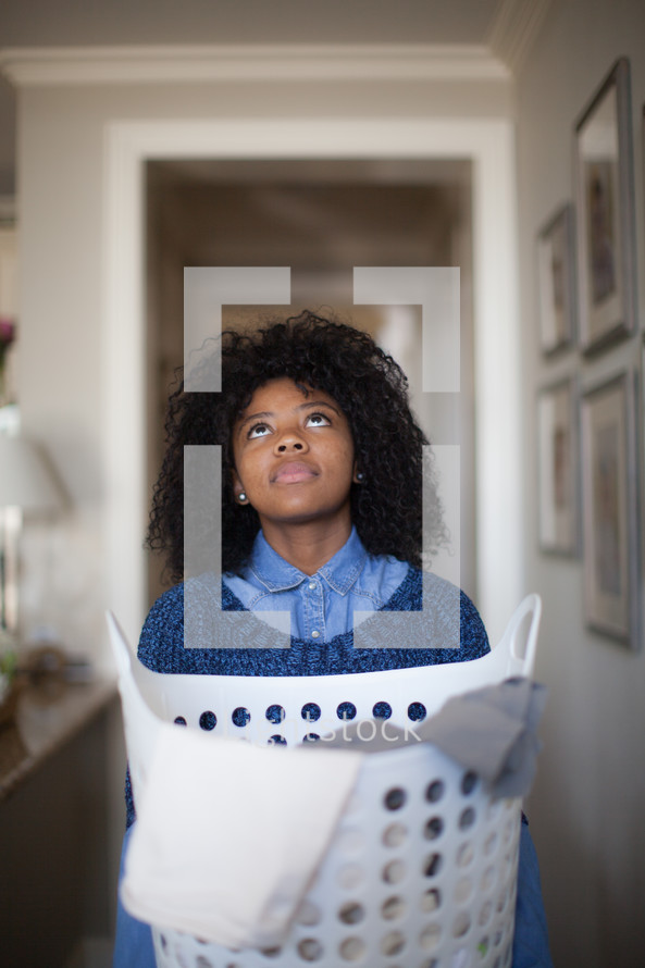 a woman holding a laundry basket looking up to God 