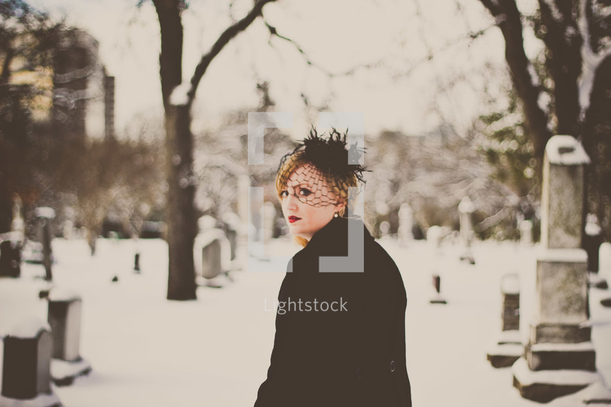 grieving woman in black in a snow covered cemetery 