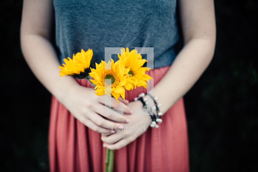 a girl holding a bouquet of sunflowers 