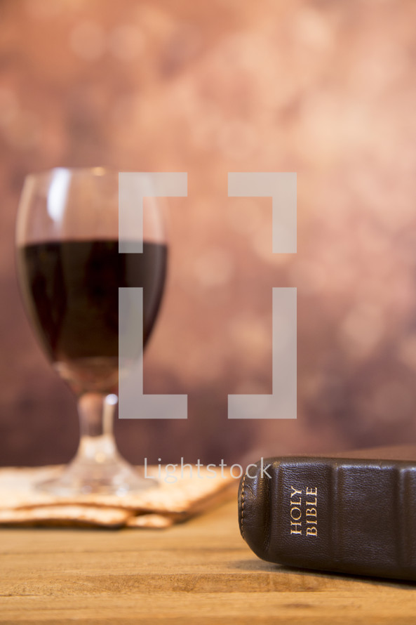 communion wine glass, unleavened bread, and Bible 