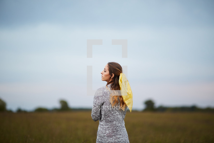 a woman in a sweater standing in a field 