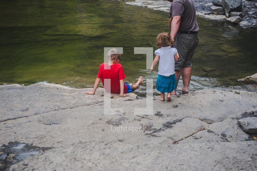 family standing at the edge of a river 