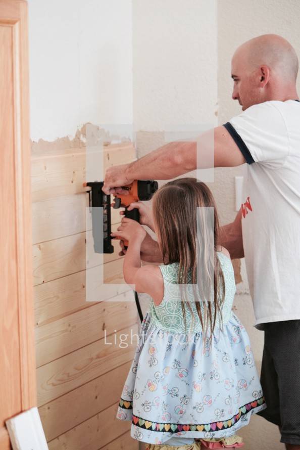father and daughter using a nail gun to put up shiplap
