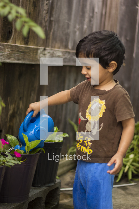toddler boy watering the garden 