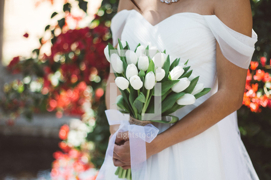 torso of a bride holding white tulips 