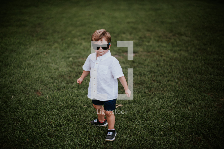 toddler in grass wearing sunglasses 