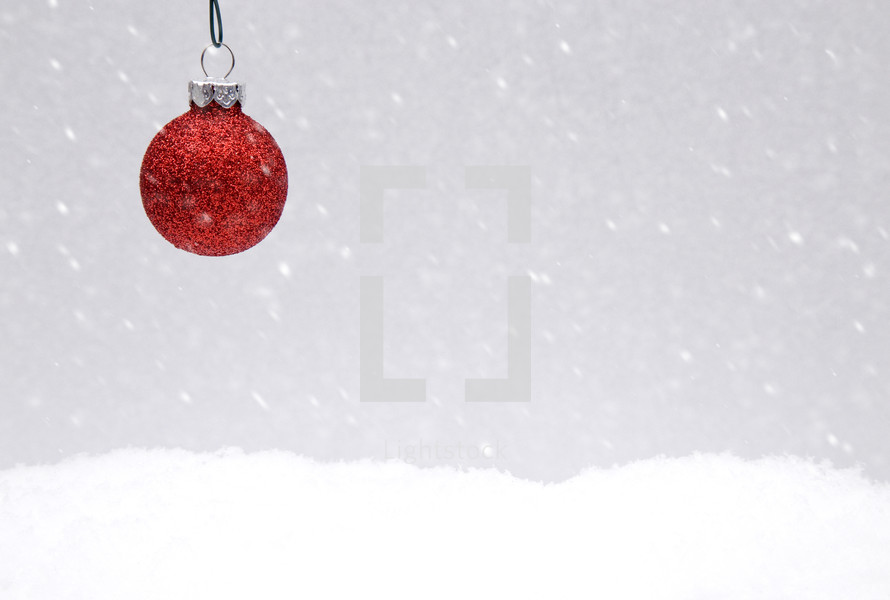 single red ornament over snow scene 
