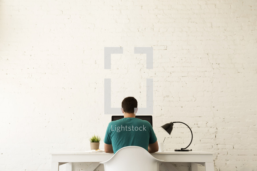 man sitting at a desk working on a computer 