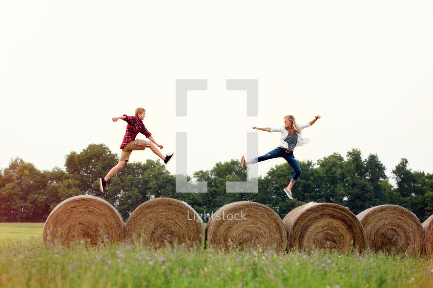 man and woman running on hay bales 