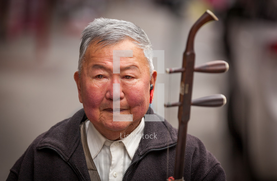 an elderly man holding an stringed instrument 