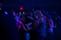 young praying over each other at a worship service 