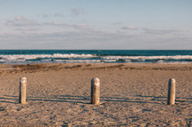 posts in the sand on a beach 