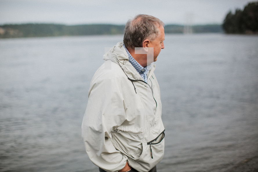 a man standing on a river shore in a jacket 