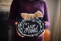 a woman holding a give thanks plaque 