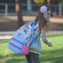 a little girl with a book bag standing in front of her school 