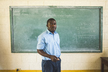 Teacher in front of a chalkboard in a classroom.