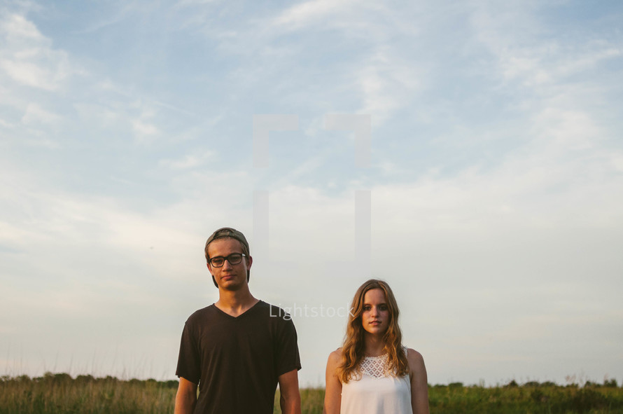 A young man and woman standing in a field.