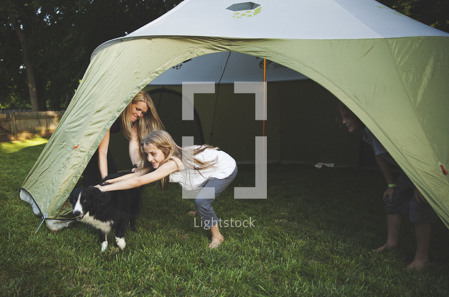 A family setting up a tent in the backyard. 