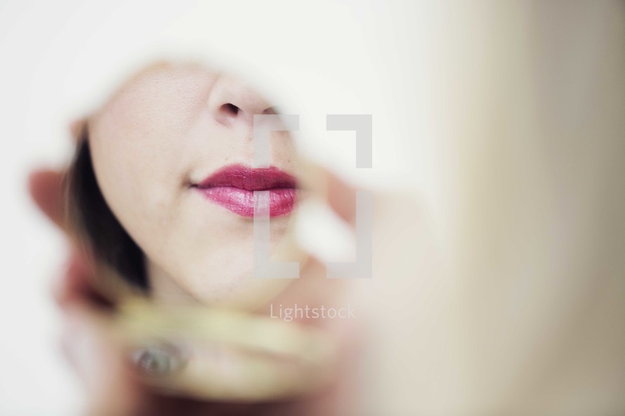 woman with red lipstick looking in a mirror 