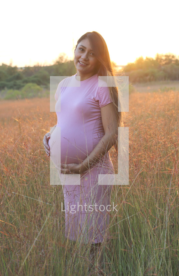 a pregnant woman standing in a field 