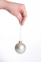 a hand holding a white Christmas ornament 