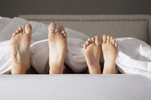 Parent's and Child's feet sticking out from the blanket at the end of the bed.