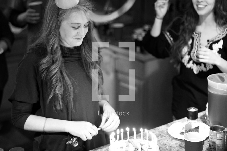 woman blowing out the candles of her birthday cake 