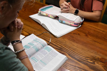 Young women praying over Bibles in Bible study time in discipleship group