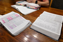 Three open Bibles on wooden table in kitchen during Bible study