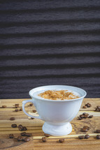 Delicious home made Cappuccino, in a white cup, on a wooden table. With coffee beans. Home made Coffee.