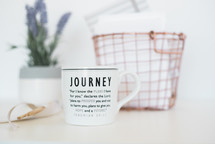 Journey message on a coffee mug, wire basket, and lavender house plant 