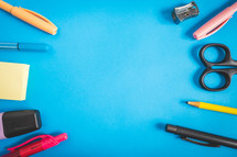 Different kind of school/office supplies for studying, on a blue background. Back to school.