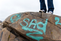 woman standing on a rock with the word sad spray painting on the side 