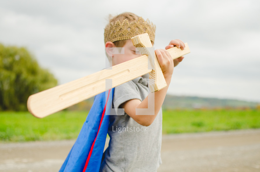 a boy in a crown holding a wooden sword 