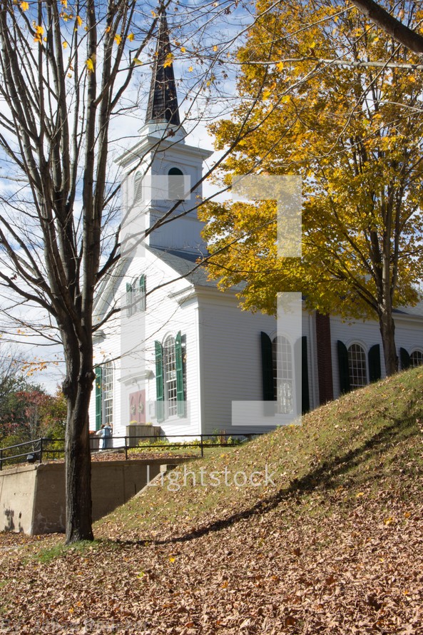 Church surrounded by fall foliage and fallen leaves,