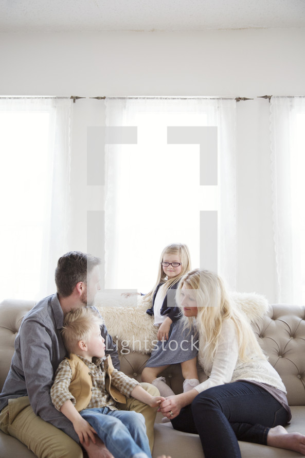 A family of four sits together on a couch.