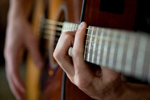 hands on the strings of a guitar 