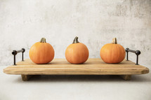 Three pumpkins on a wooden tray