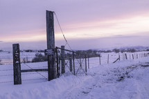 The barbed wire fence leads along the winter landscape scenery after a snow storm
