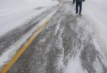 a man walking alone on the road in a blizzard