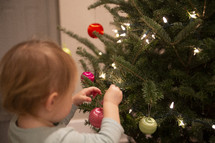 Small child hanging ornaments on a Christmas tree