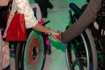 couple in wheelchairs holding hands 